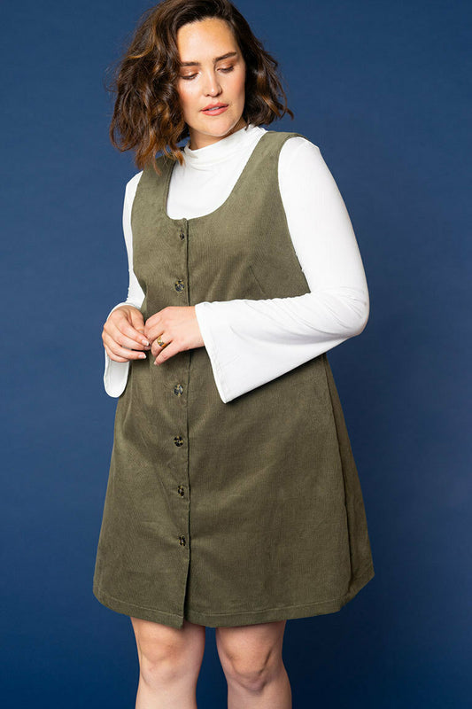 Woman wearing a green skirt and vest over a white blouse against a blue background