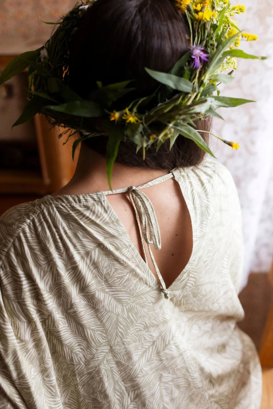 Person wearing a floral headpiece with a neutral background