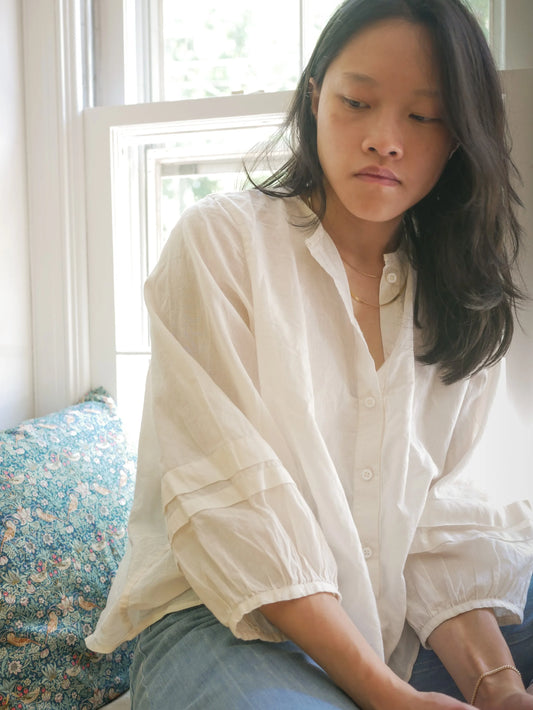 Woman wearing a white blouse sitting on a floral couch.