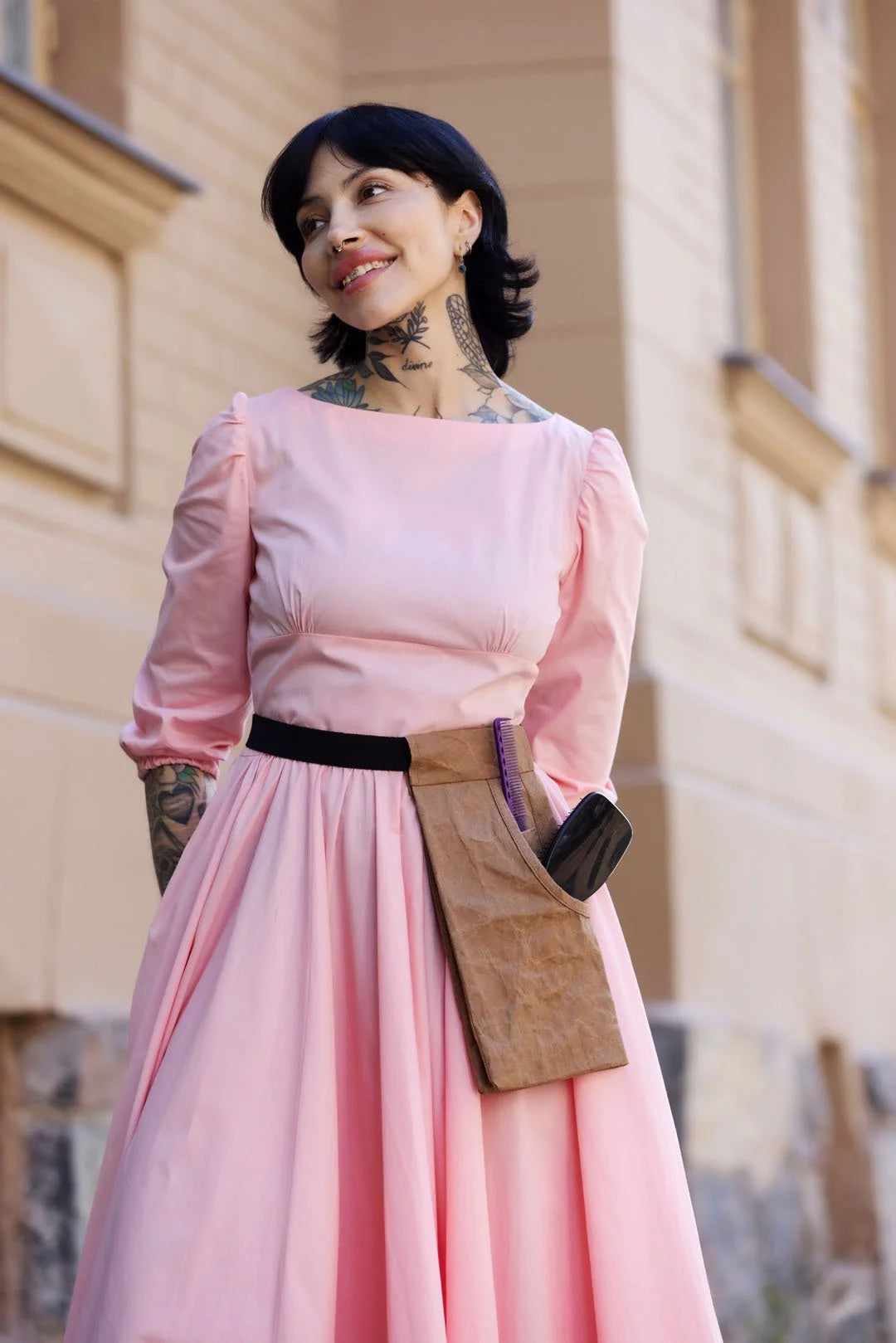 Woman in a pink dress standing in front of a building