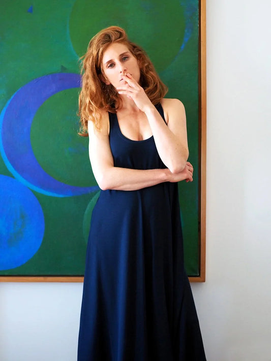 Woman in a blue dress standing in front of a colorful abstract painting.