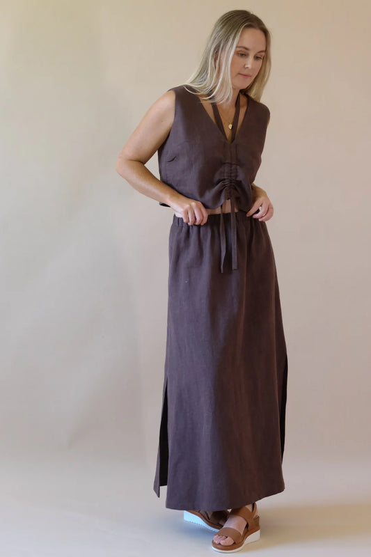 Woman wearing a long brown dress against a plain background