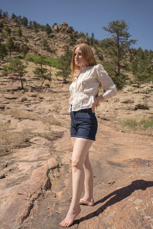 Woman standing on a rocky landscape with trees in the background