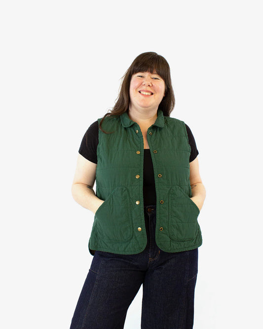A person wearing a green quilted Wildwood vest with a collar.