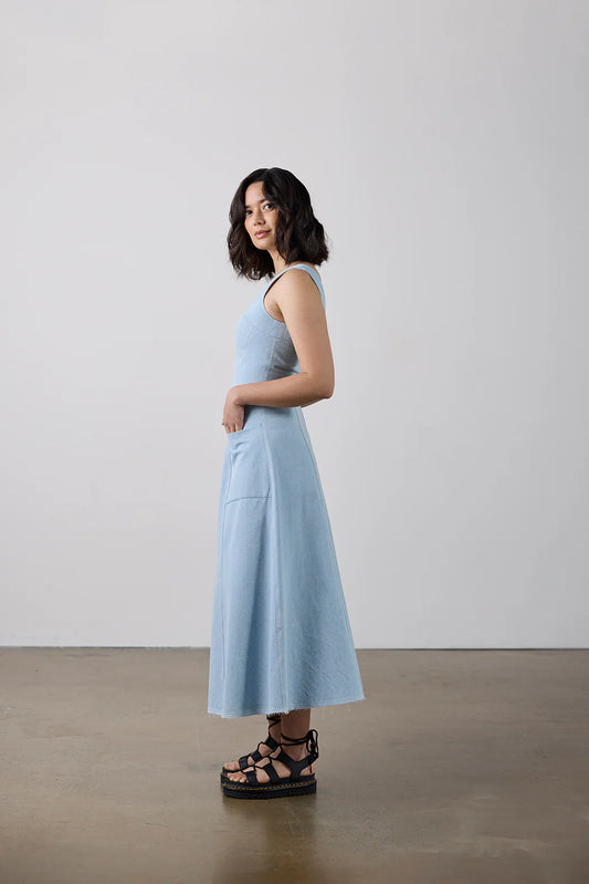 Woman wearing a light blue dress standing against a plain background