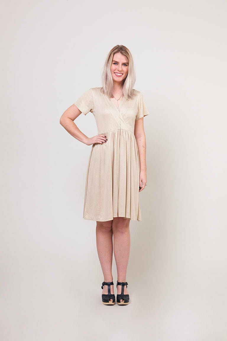 Woman wearing a beige dress against a plain background