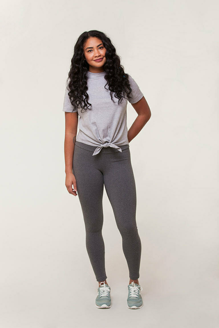 Woman wearing a gray t-shirt and leggings on a white background