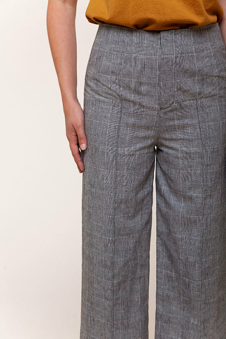 Person wearing gray checkered pants with a plain background