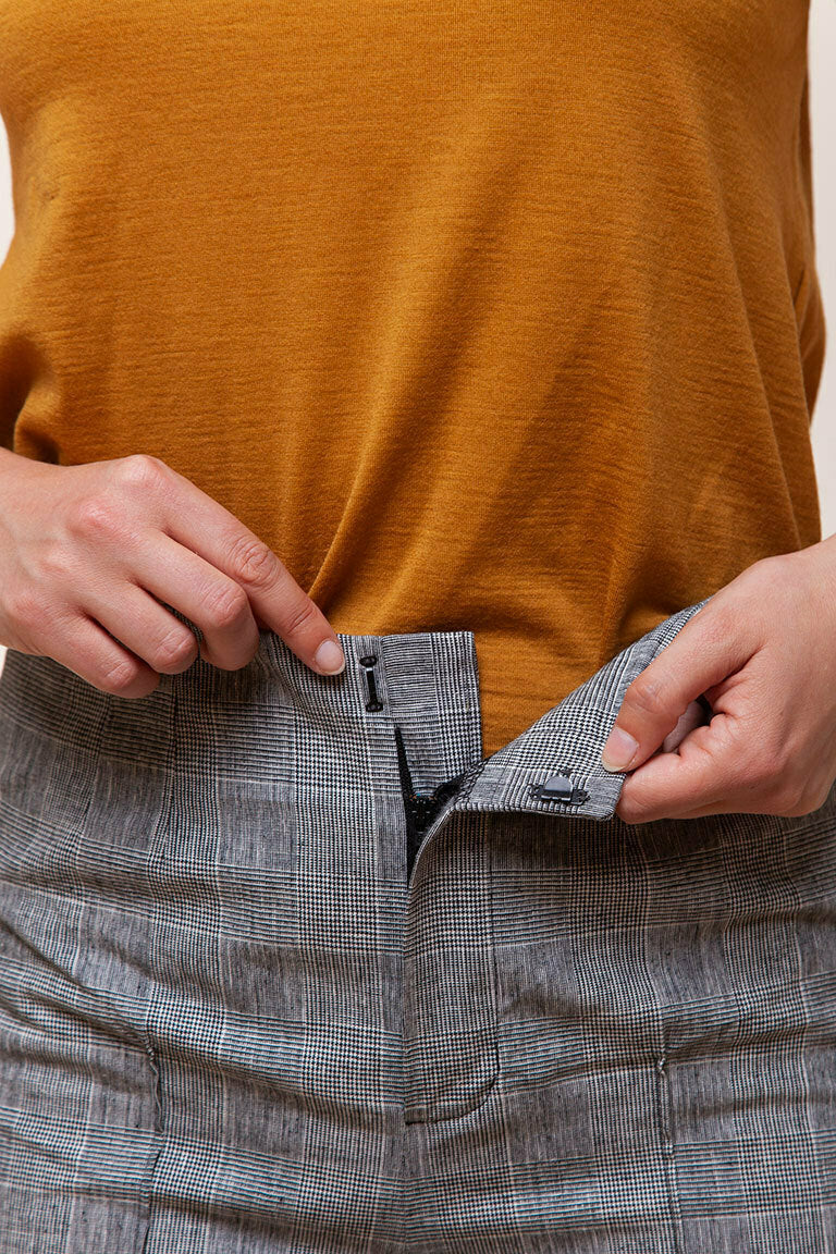 Person wearing a mustard yellow top and gray plaid pants, focusing on the waist area.
