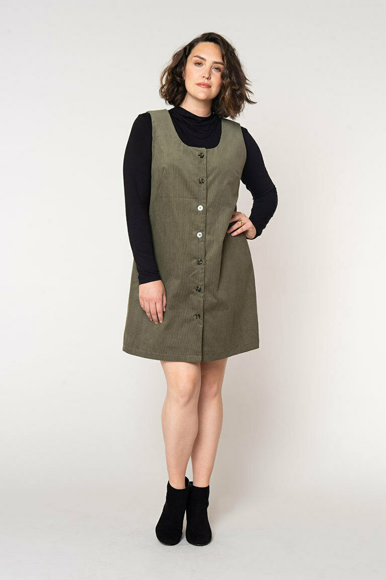 Woman wearing a green dress over a black top on a white background