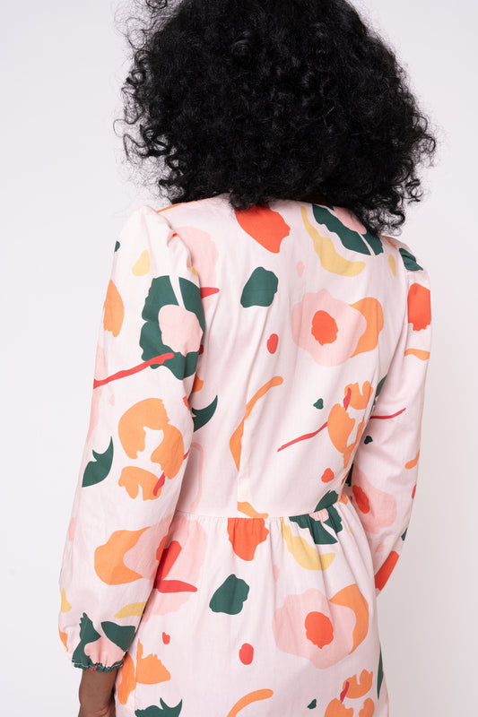 Person wearing a floral-patterned long-sleeve shirt against a white background