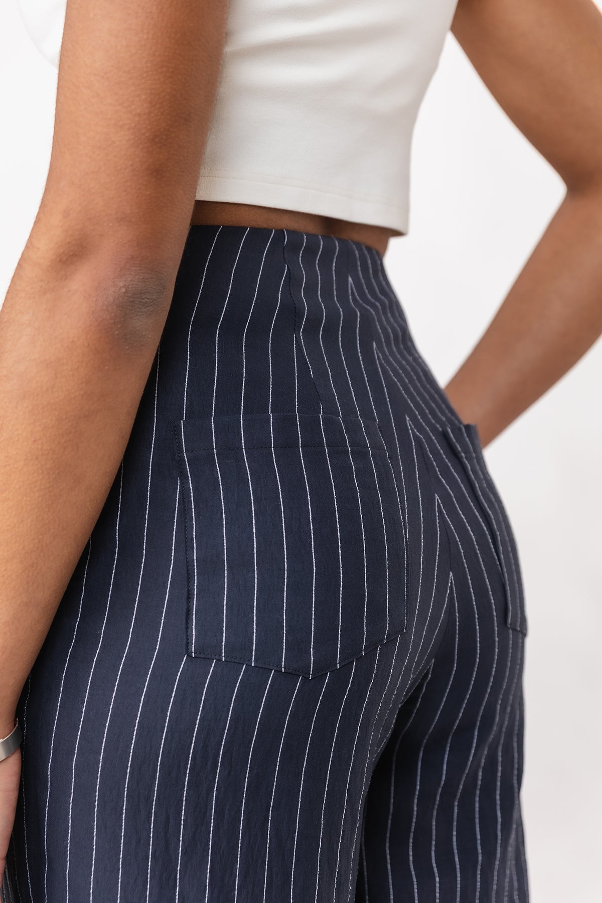 Navy pinstripe pants worn by a person on a plain background