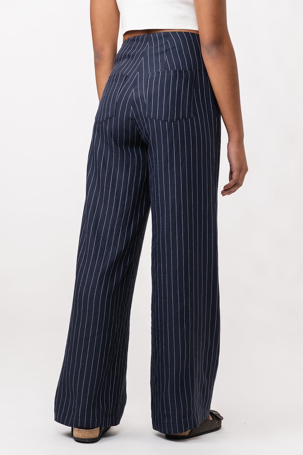 Navy pinstripe pants worn by a person on a white background