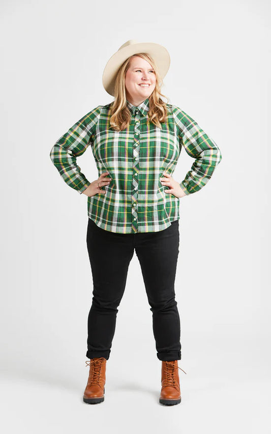 Person wearing a green plaid shirt, black pants, brown boots, and a beige hat on a white background