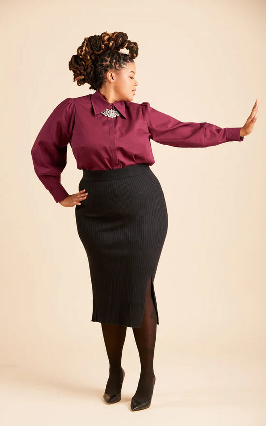 Woman wearing a burgundy blouse and black skirt on a beige background