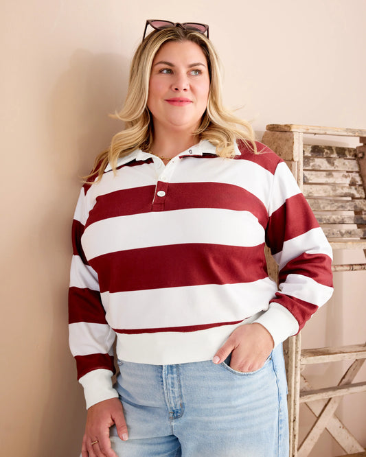 Woman wearing a red and white striped shirt with light blue jeans against a neutral background