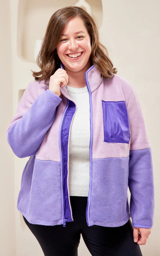 Person wearing a purple and pink fleece jacket with a white background