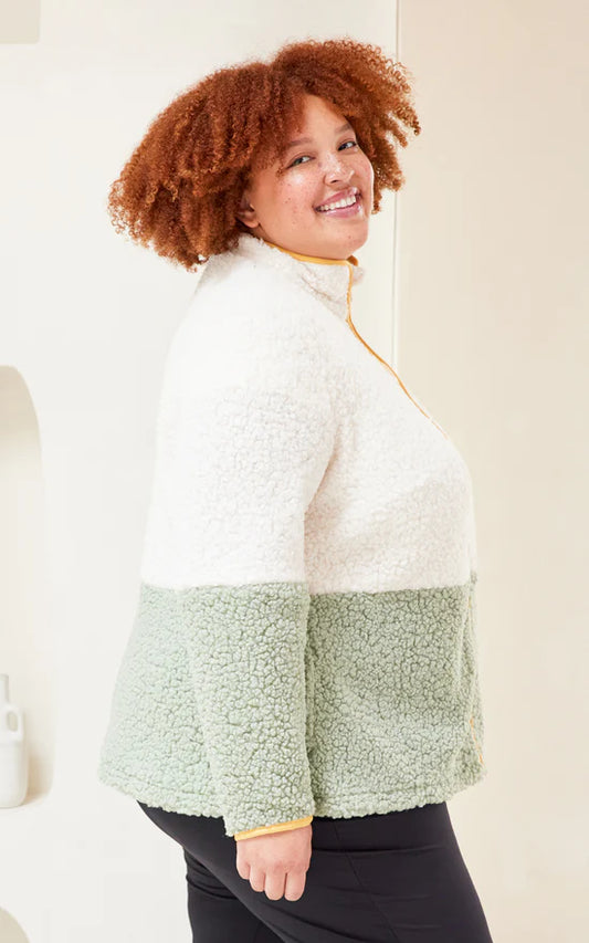 Person wearing a white and green color-blocked jacket against a plain background