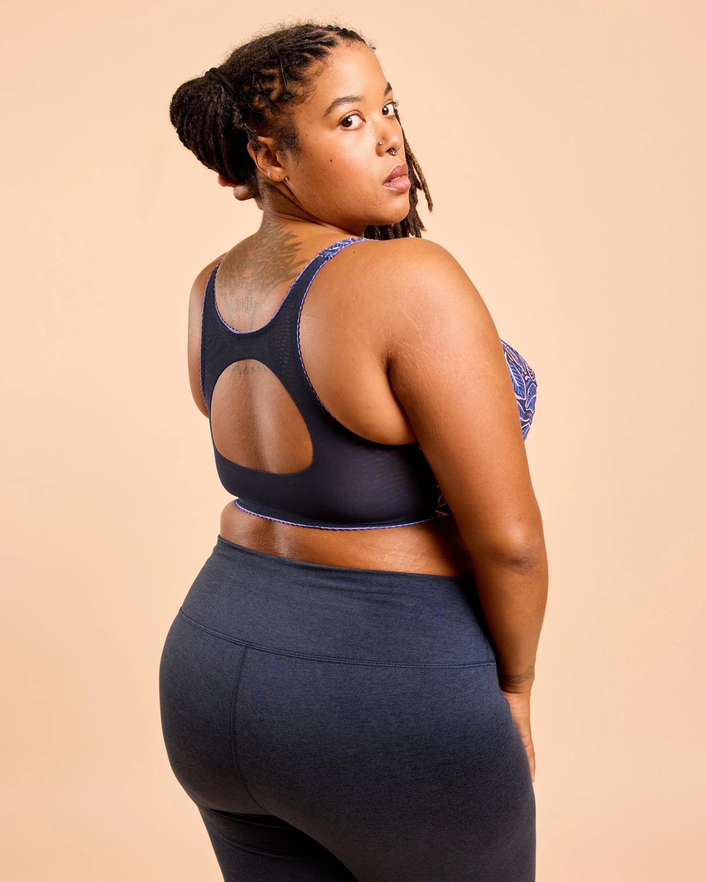 Woman wearing a black sports bra and leggings on a beige background