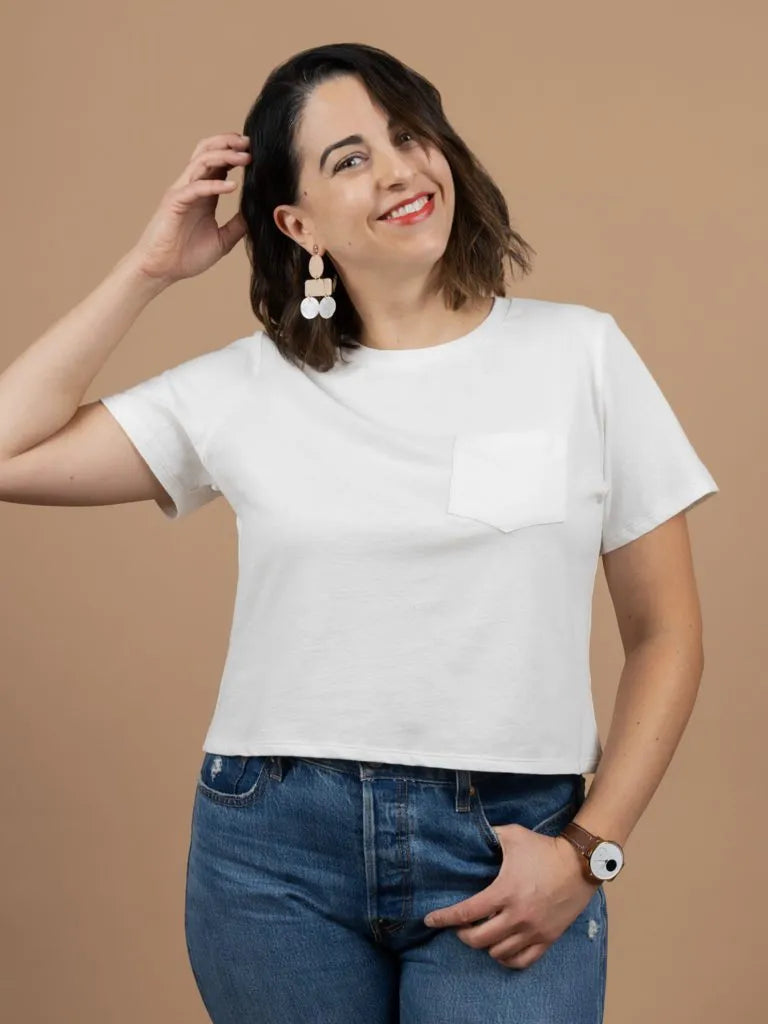Woman wearing a white t-shirt and blue jeans against a beige background