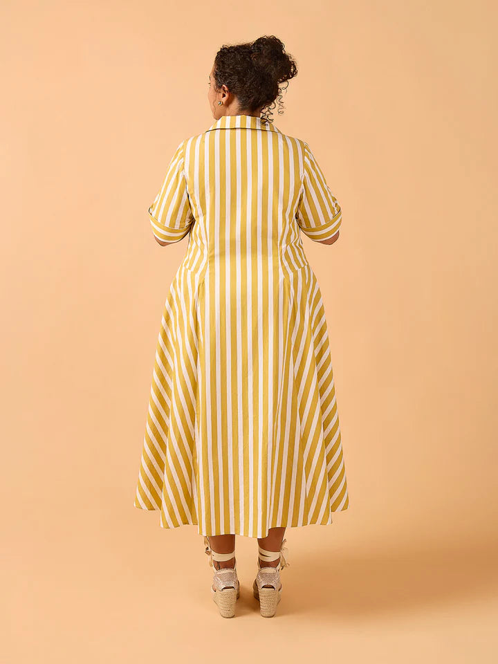 Woman wearing a yellow and white striped dress against a beige background