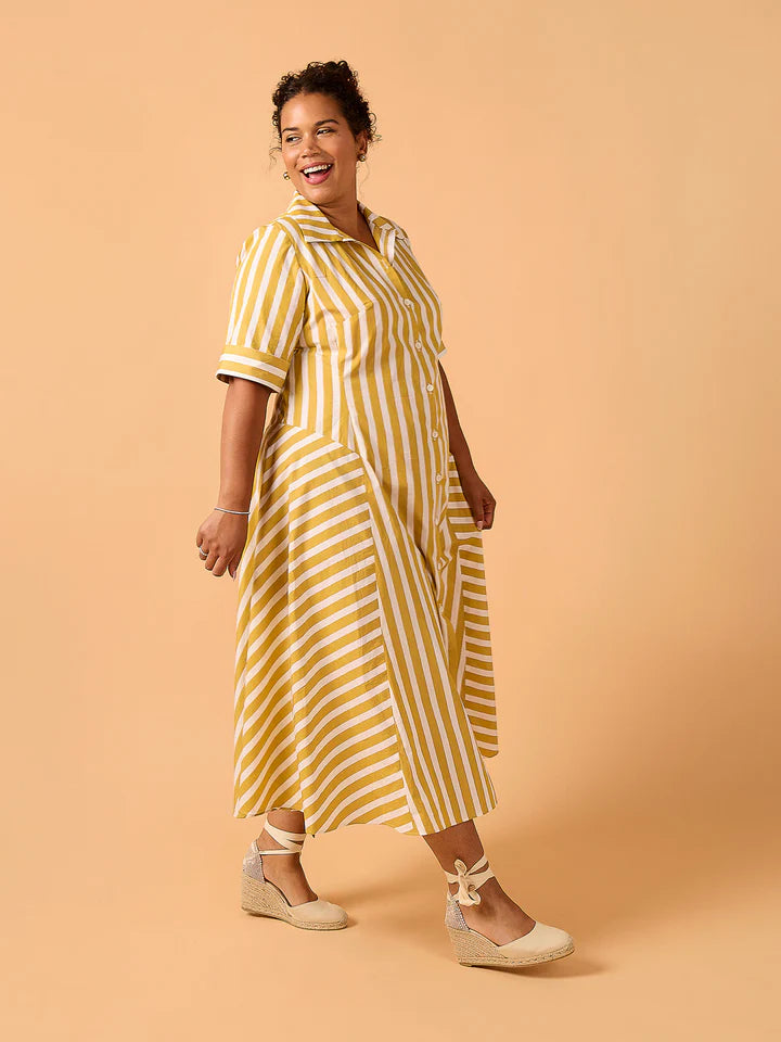 Woman wearing a yellow and white striped dress on a beige background