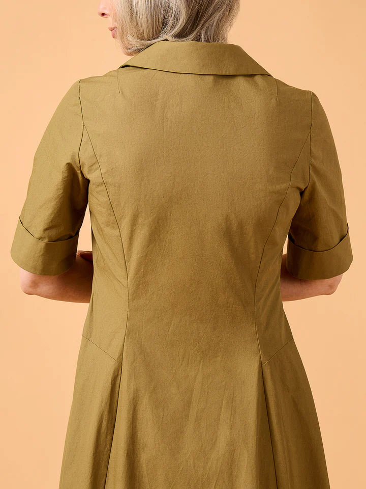 Person wearing a green dress against a beige background
