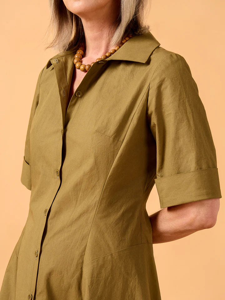 Person wearing a green dress against a peach background