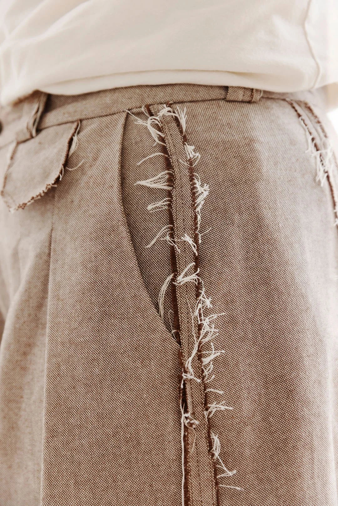 Close-up of a brown denim skirt with a visible tear and stitching detail.