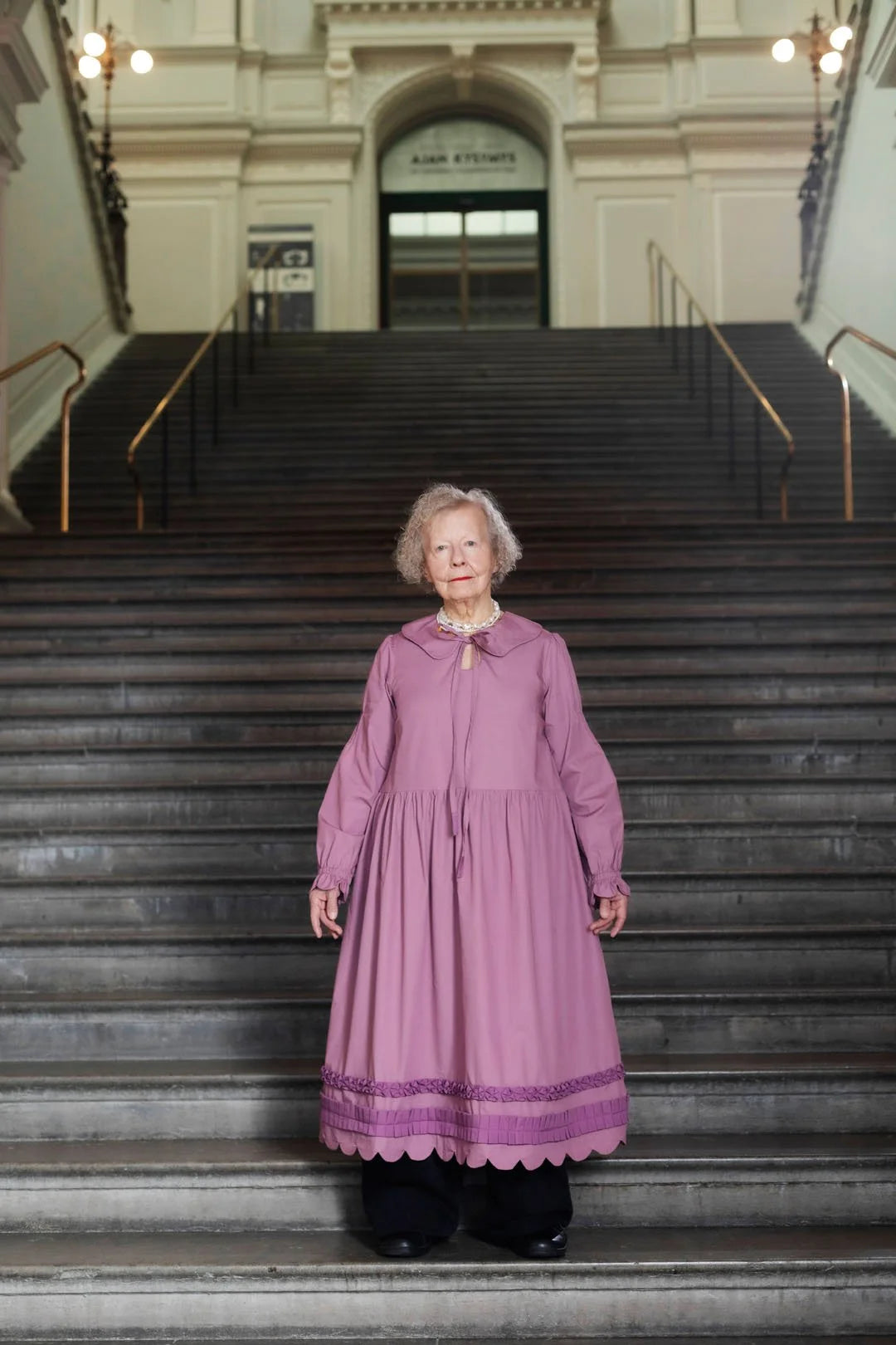 Woman in a purple dress standing on a staircase inside a building