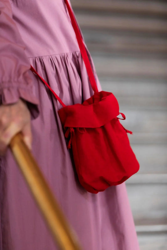 Red bag held by a person wearing a pink dress with a blurred background