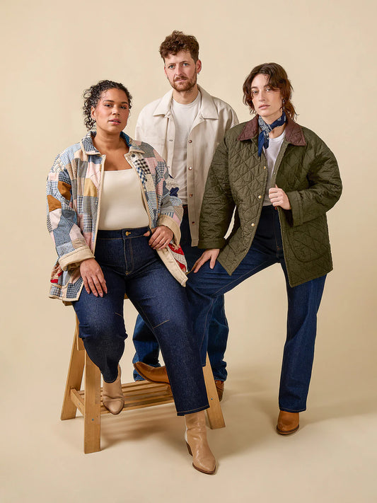 Three people wearing jackets and jeans against a beige background