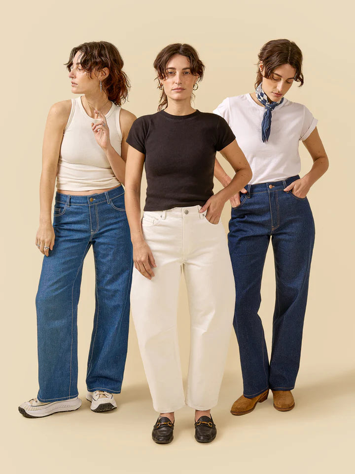 Three women wearing different styles of jeans against a beige background