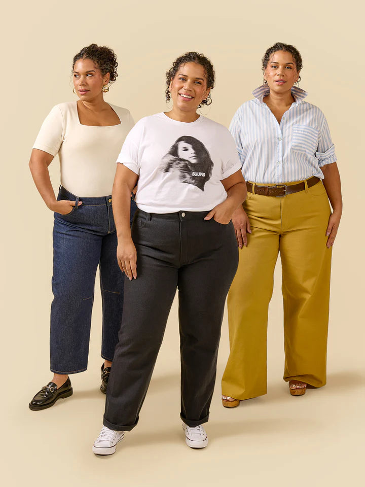 Three women standing side by side wearing different outfits on a beige background