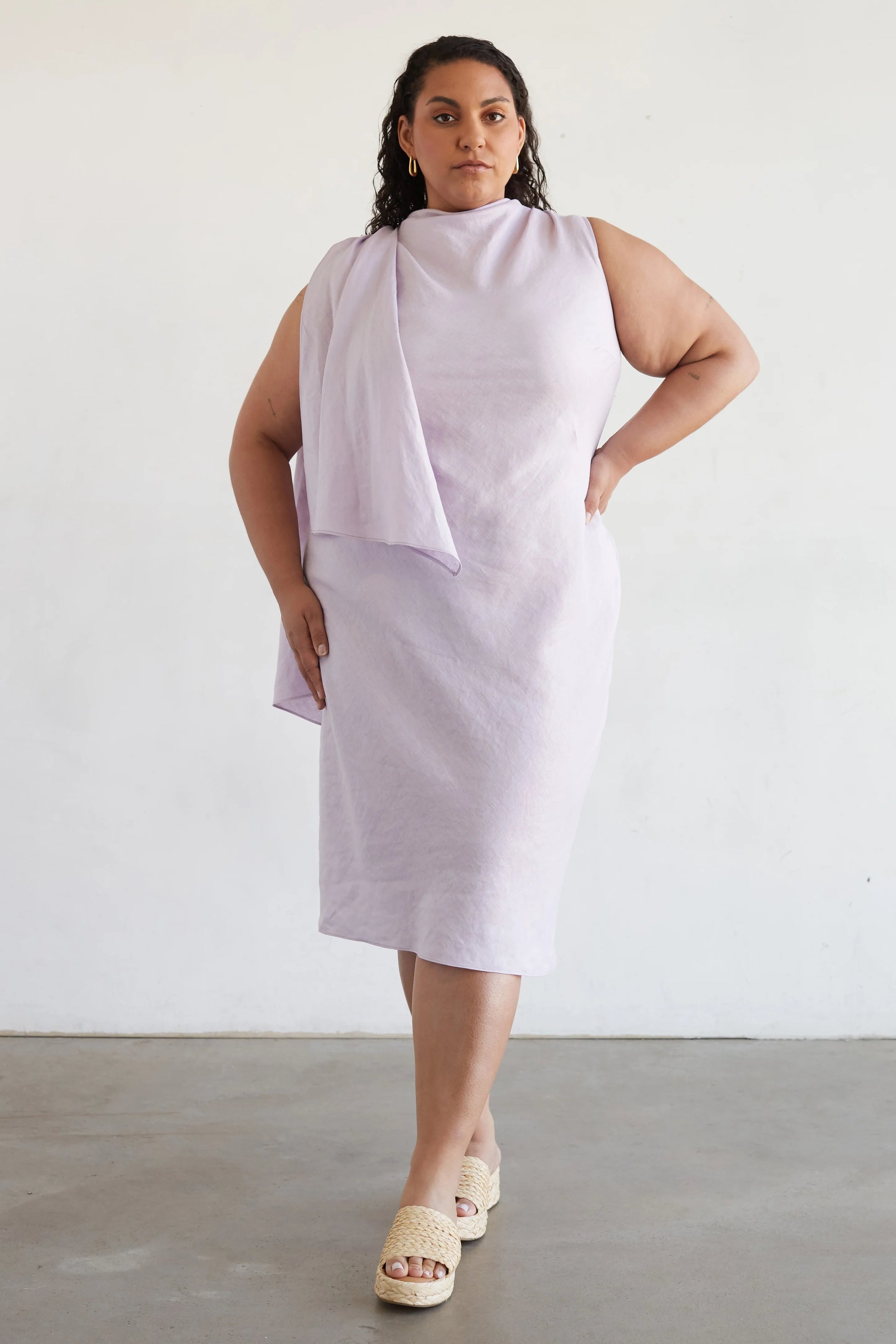 Woman wearing a white sleeveless dress against a plain background