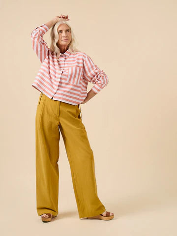 Woman wearing a striped shirt and wide-leg pants on a beige background