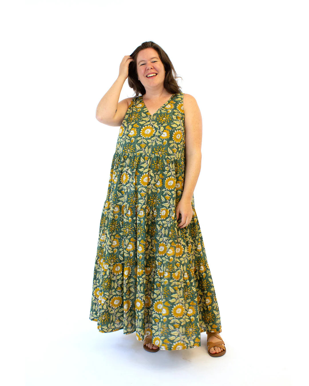 Woman wearing a green print long flowy dress on a white background