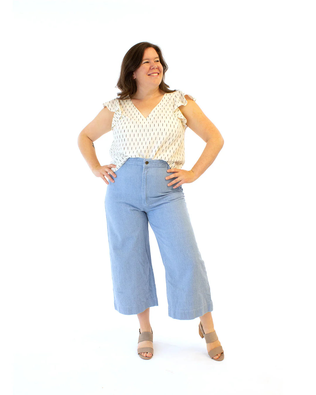 Woman wearing a white print top with butterfly sleeves on a white background
