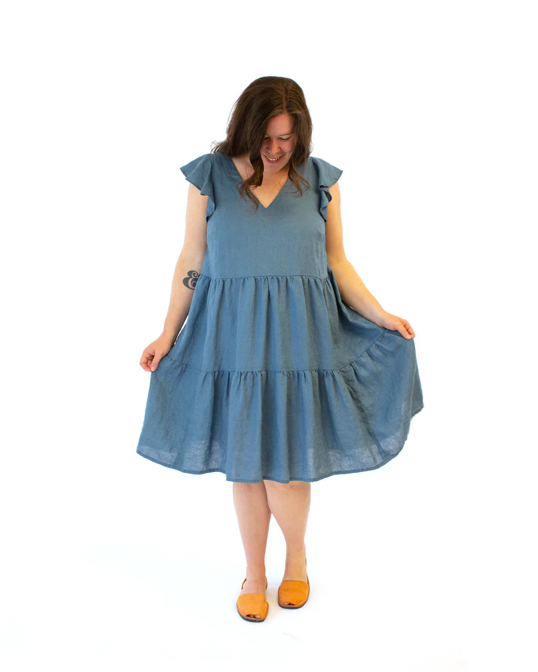 Woman wearing a blue flowy dress with butterfly sleeves on a white background
