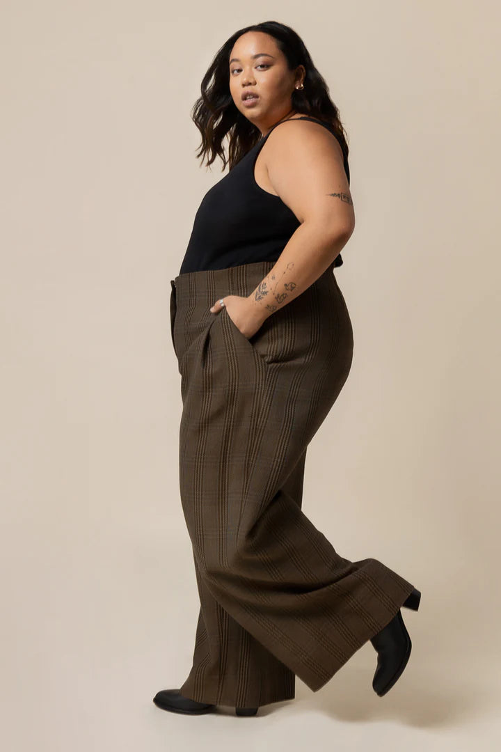 Woman wearing brown wide-leg pants and a black top on a beige background