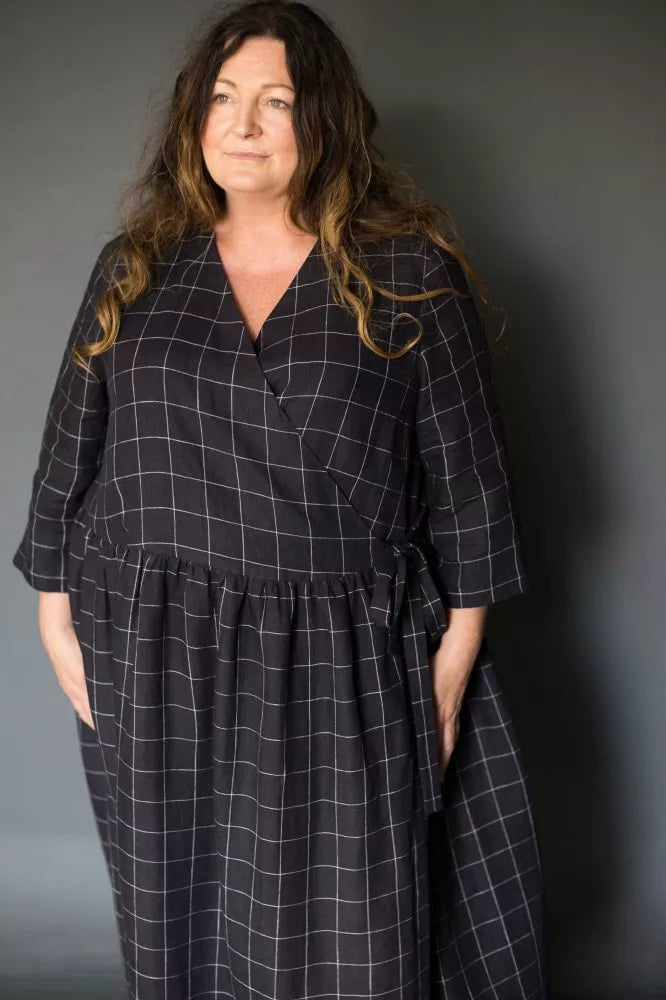 Woman wearing a black checkered dress against a gray background