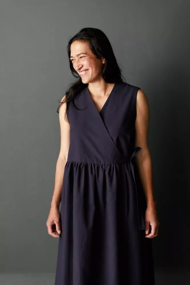 Woman wearing a dark blue dress against a gray background