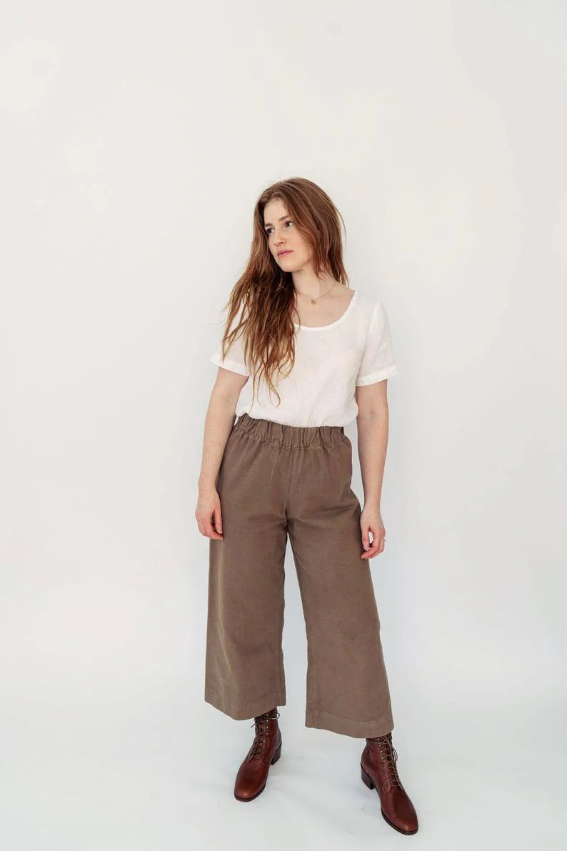 Woman wearing a white top and brown pants on a white background