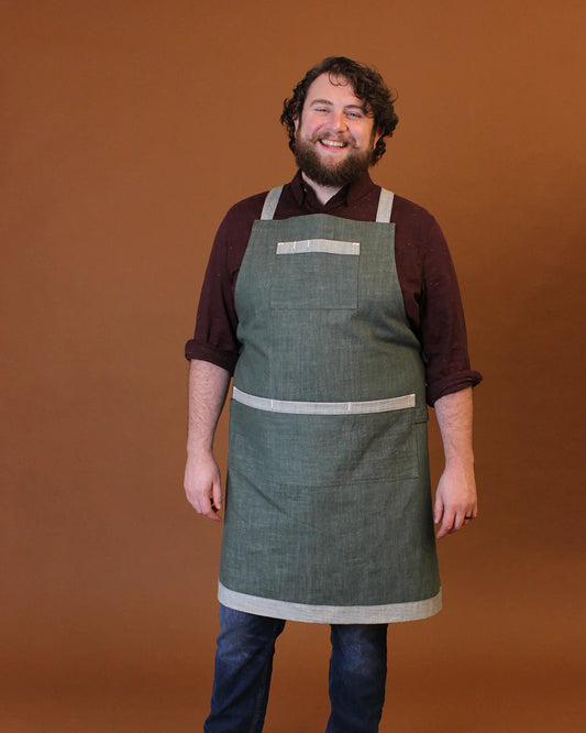 Man wearing a green apron against a brown background