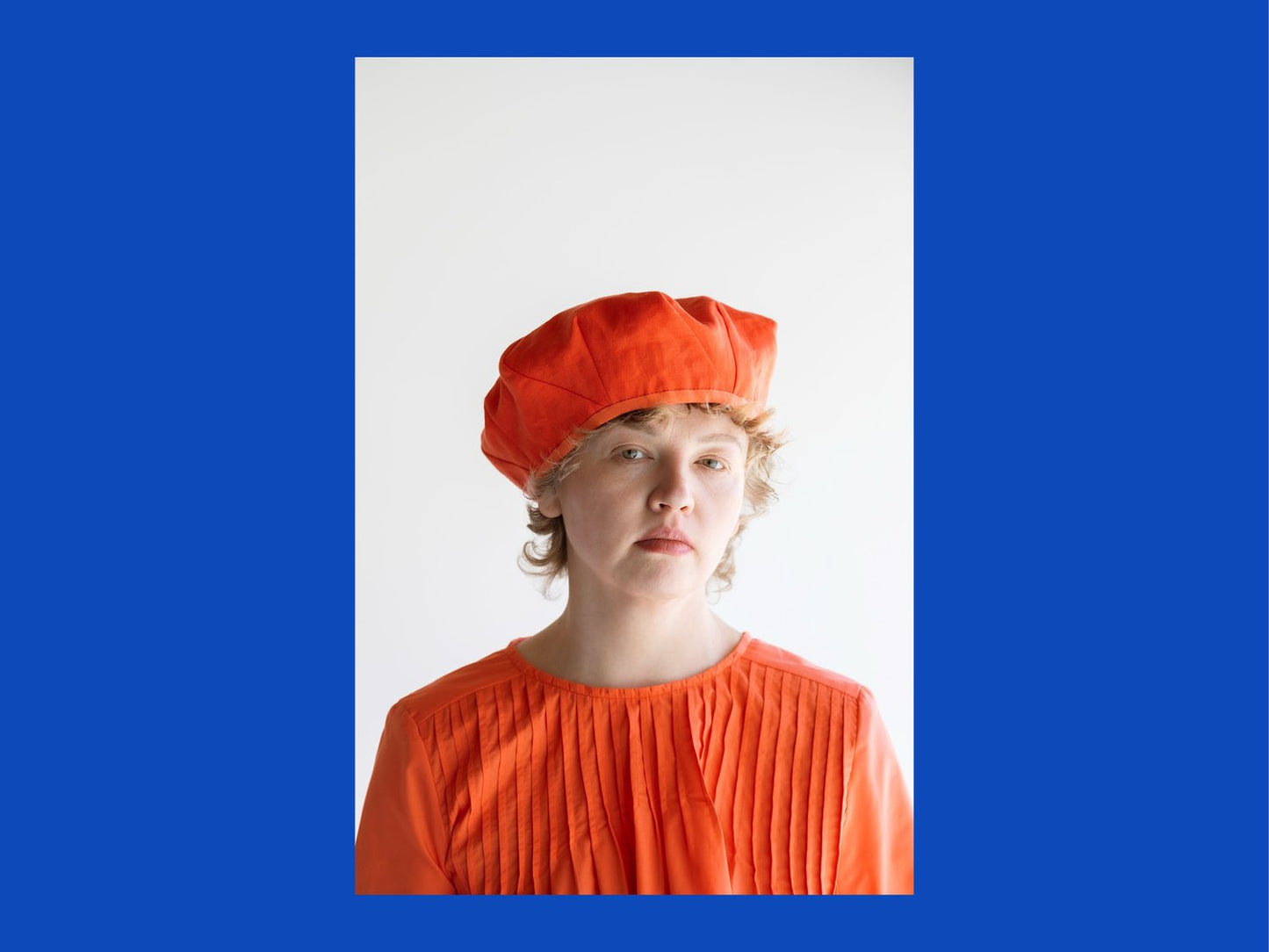 Person wearing an orange outfit with a matching hat on a blue background