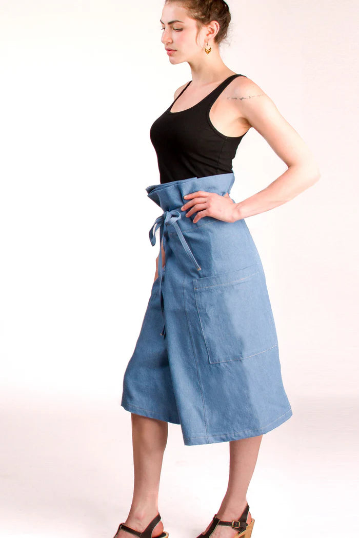 Woman wearing a blue apron over a black top on a white background