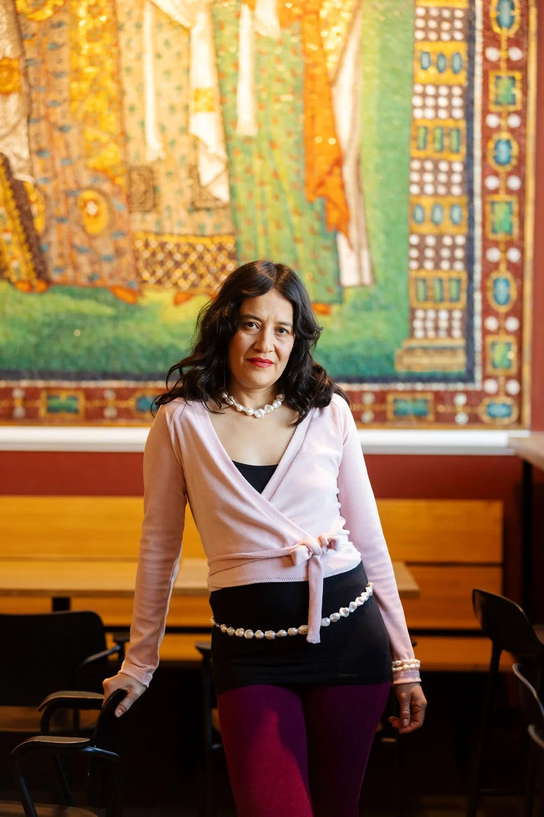 Woman posing in front of a colorful tapestry