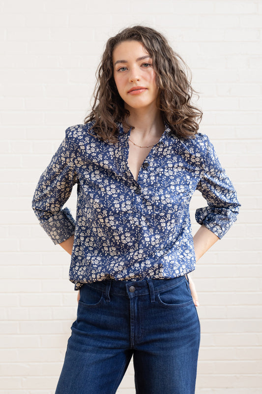 Woman wearing a blue floral blouse and jeans against a white background