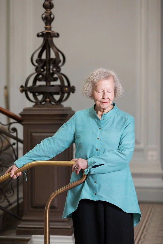 Woman in a teal shirt standing indoors with decorative elements in the background