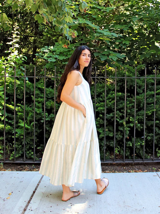 Woman in a white dress standing outdoors with greenery in the background
